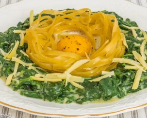 Oeuf dans nid de pâtes sur lit d’épinards